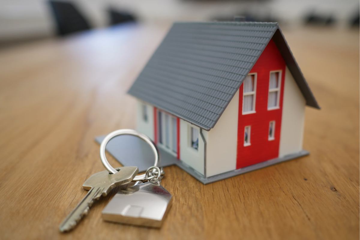white-and-red-wooden-house-miniature-on-brown-table