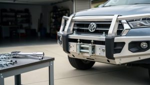 A bull bar partially installed on the front of an Australian ute with a torque wrench and tools on a work surface in front of the vehicle.